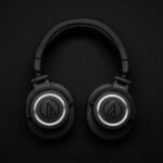 Close-up of black over-ear headphones on a black background, showcasing modern design.
