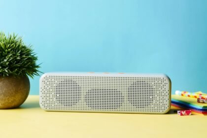 Modern wireless speaker placed elegantly with a potted plant and colorful stationery.